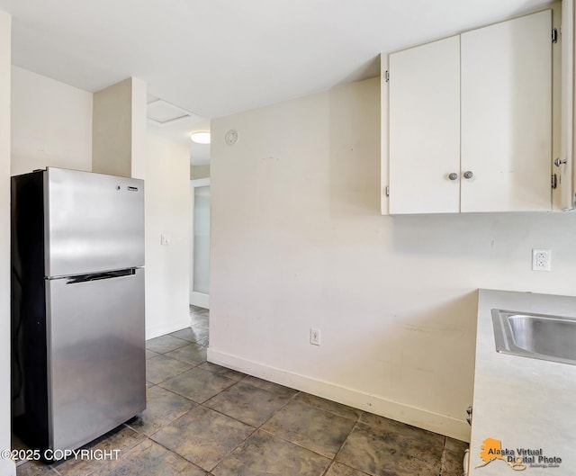 124 E 7th Ave, Anchorage, AK 99501 - kitchen with freestanding refrigerator, white cabinetry, and light countertops