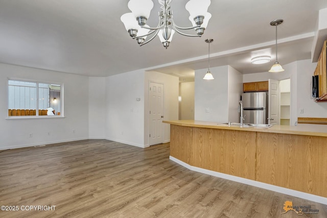 6314 Whispering Loop # 30A, Anchorage, AK 99504 - kitchen with freestanding refrigerator, a chandelier, light wood-type flooring, pendant lighting, and light countertops