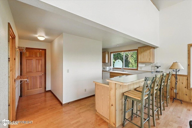 34494 Grizzly Ln, Sterling, AK 99672 - kitchen featuring light wood-style flooring, a peninsula, a breakfast bar area, light countertops, and dishwashing machine