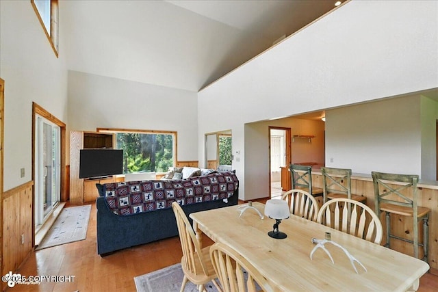 34494 Grizzly Ln, Sterling, AK 99672 - dining room featuring light wood-style floors, high vaulted ceiling, a wainscoted wall, and wooden walls