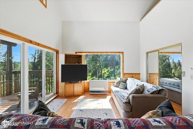 34494 Grizzly Ln, Sterling, AK 99672 - living room featuring a towering ceiling, light wood finished floors, a wainscoted wall, and wood walls