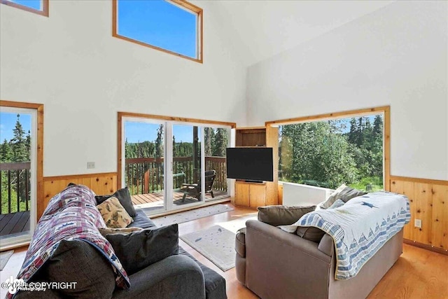 34494 Grizzly Ln, Sterling, AK 99672 - living room with high vaulted ceiling, healthy amount of natural light, wooden walls, wainscoting, and light wood-style floors