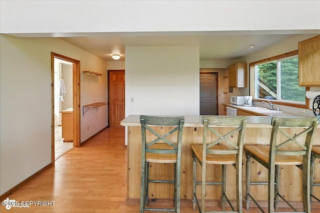 34494 Grizzly Ln, Sterling, AK 99672 - kitchen featuring light wood-style floors, light countertops, a peninsula, a kitchen breakfast bar, and white appliances