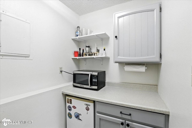 2924 Carnaby Way, Anchorage, AK 99504 - kitchen with stainless steel microwave, refrigerator, gray cabinetry, light countertops, and open shelves