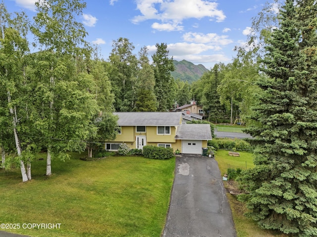 10711 Colville St, Eagle River, AK 99577 - split foyer home featuring asphalt driveway, a front lawn, a wooded view, and a mountain view