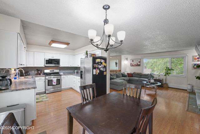 10711 Colville St, Eagle River, AK 99577 - dining area with a chandelier, light wood-style flooring, and a textured ceiling