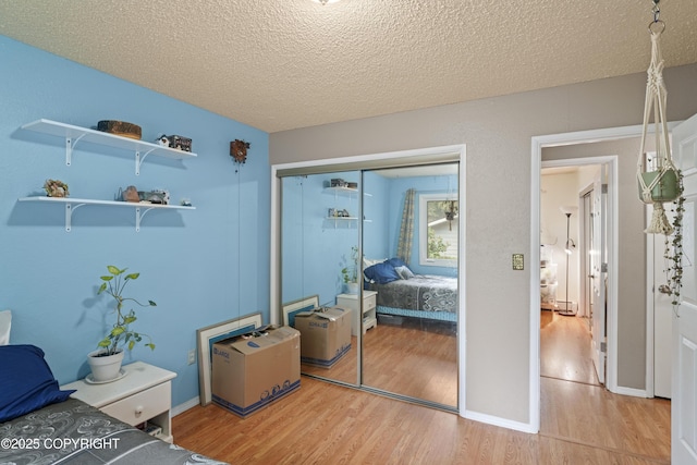 10711 Colville St, Eagle River, AK 99577 - bedroom featuring light wood-style floors, a closet, and a textured ceiling