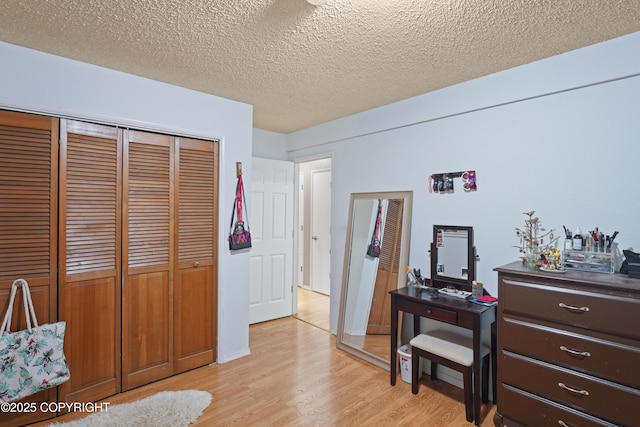 10711 Colville St, Eagle River, AK 99577 - bedroom with light wood-style flooring, a closet, and a textured ceiling