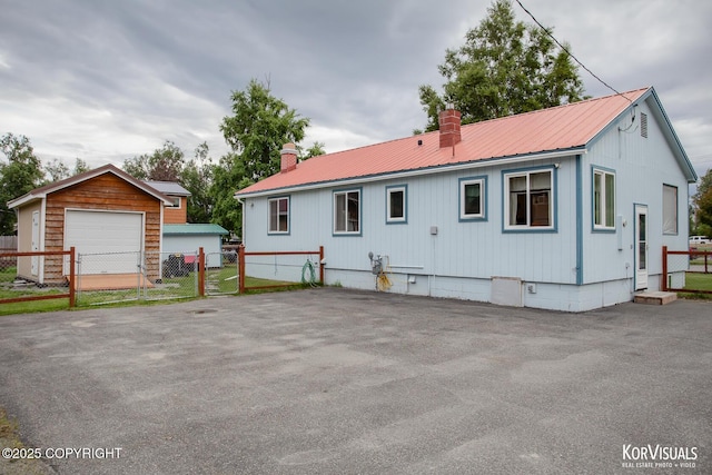 203 S Cobb St, Palmer, AK 99645 - rear view of house with a chimney, a metal roof, a garage, and an outbuilding
