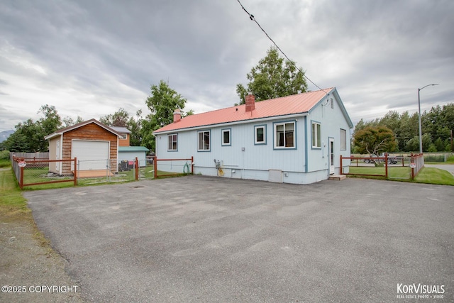 203 S Cobb St, Palmer, AK 99645 - view of front of home with a metal roof, a chimney, a gate, an outbuilding, and a detached garage