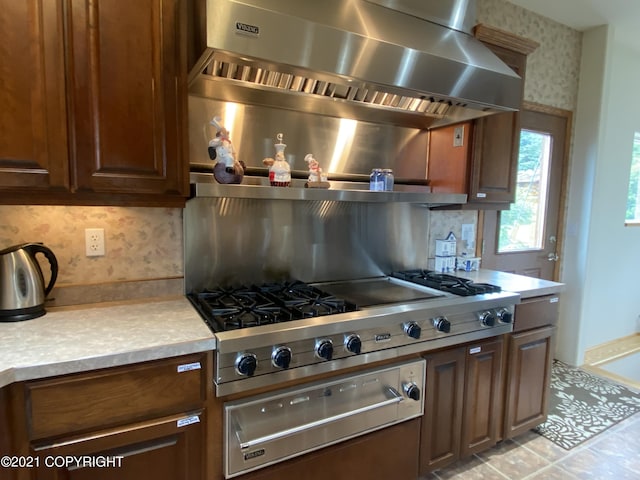 60871 Bear Creek Dr, Homer, AK 99603 - kitchen featuring wall chimney exhaust hood, a warming drawer, stainless steel gas cooktop, light countertops, and tasteful backsplash