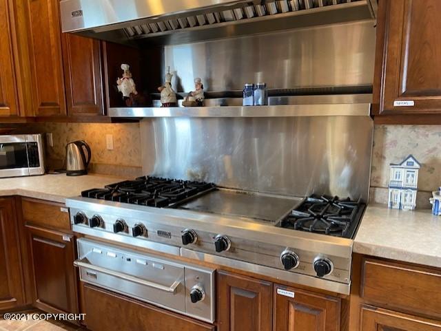 60871 Bear Creek Dr, Homer, AK 99603 - kitchen featuring tasteful backsplash, appliances with stainless steel finishes, light countertops, and brown cabinetry