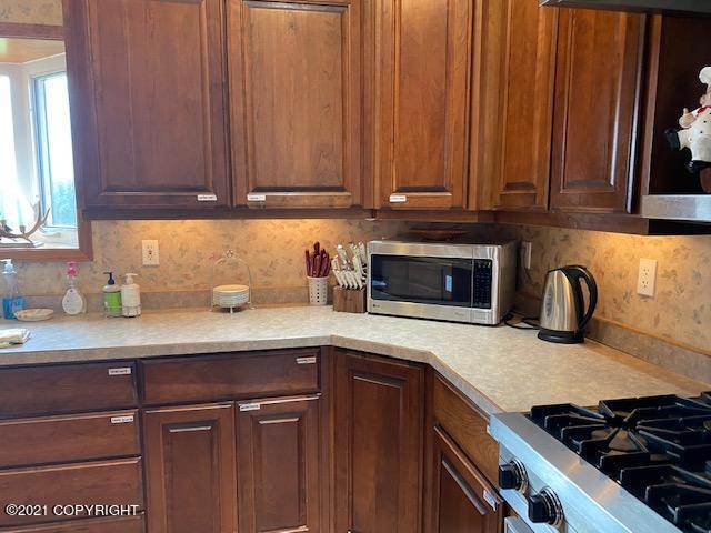 60871 Bear Creek Dr, Homer, AK 99603 - kitchen with stainless steel microwave, light countertops, and decorative backsplash