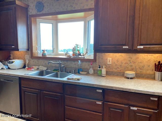 60871 Bear Creek Dr, Homer, AK 99603 - kitchen featuring stainless steel dishwasher, plenty of natural light, wallpapered walls, and light countertops