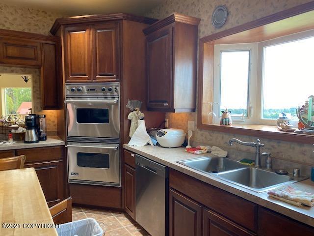 60871 Bear Creek Dr, Homer, AK 99603 - kitchen featuring appliances with stainless steel finishes, wallpapered walls, light countertops, and light tile patterned floors