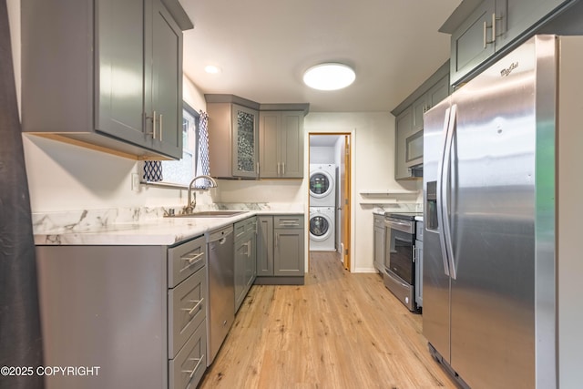 3237 Lincoln Ct, Ketchikan, AK 99901 - kitchen featuring stainless steel appliances, stacked washer / drying machine, gray cabinetry, and light wood-type flooring