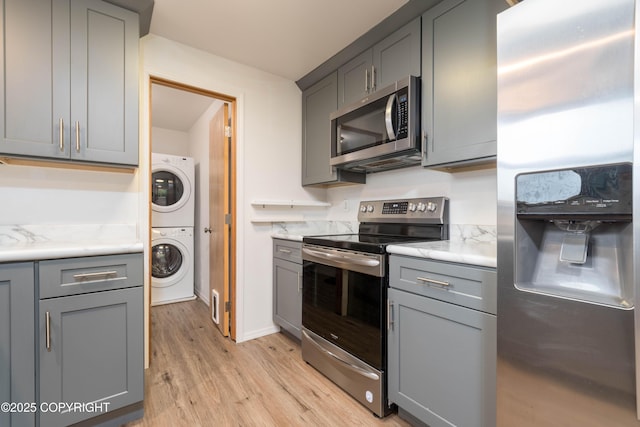 3237 Lincoln Ct, Ketchikan, AK 99901 - kitchen featuring appliances with stainless steel finishes, stacked washing machine and dryer, and gray cabinetry