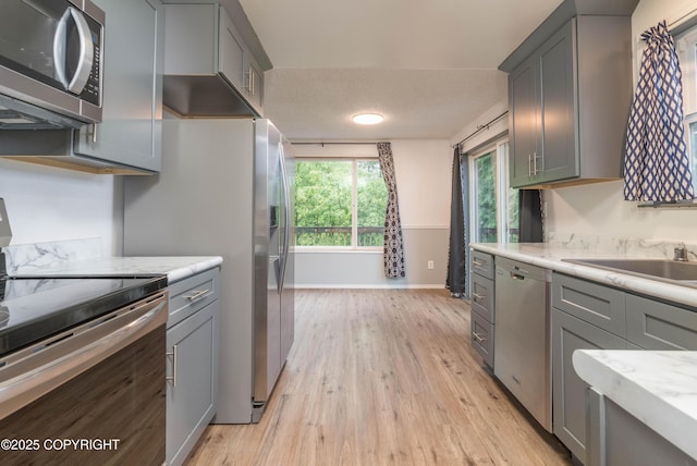 3237 Lincoln Ct, Ketchikan, AK 99901 - kitchen with appliances with stainless steel finishes, light wood-style flooring, gray cabinets, and light stone counters