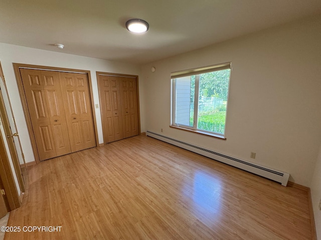 16297 E Harter Dr, Palmer, AK 99645 - unfurnished bedroom with baseboard heating, two closets, and light wood-type flooring