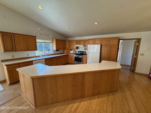 16297 E Harter Dr, Palmer, AK 99645 - kitchen with white appliances, under cabinet range hood, vaulted ceiling, brown cabinetry, and light countertops