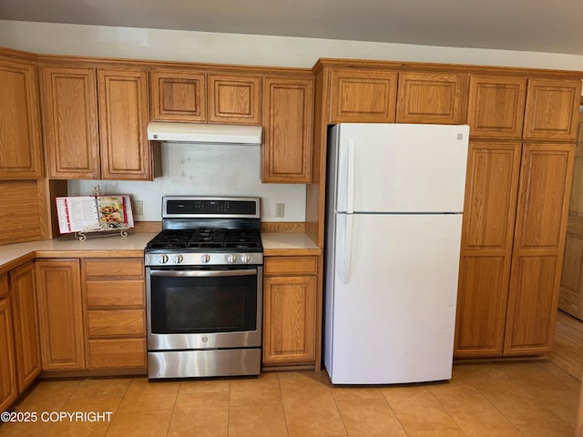 16297 E Harter Dr, Palmer, AK 99645 - kitchen featuring freestanding refrigerator, stainless steel gas range oven, under cabinet range hood, and brown cabinets