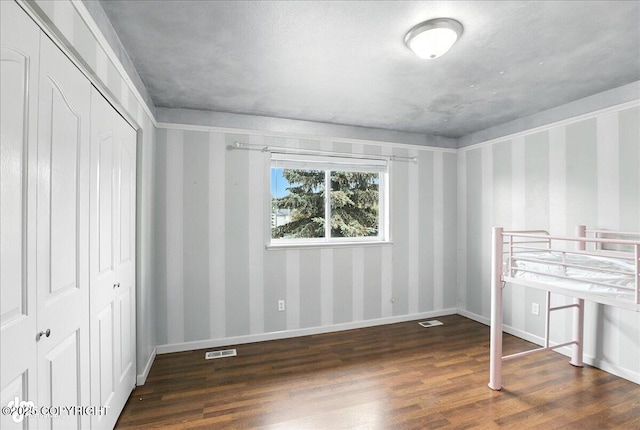 10300 Ridge Park Dr, Anchorage, AK 99507 - unfurnished bedroom with wood finished floors, a closet, and wallpapered walls