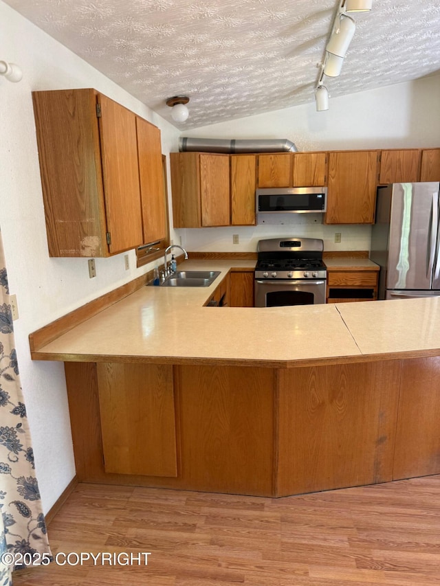 4261 E Foxtrot Ave, Wasilla, AK 99654 - kitchen featuring stainless steel appliances, brown cabinetry, track lighting, a textured ceiling, and light countertops