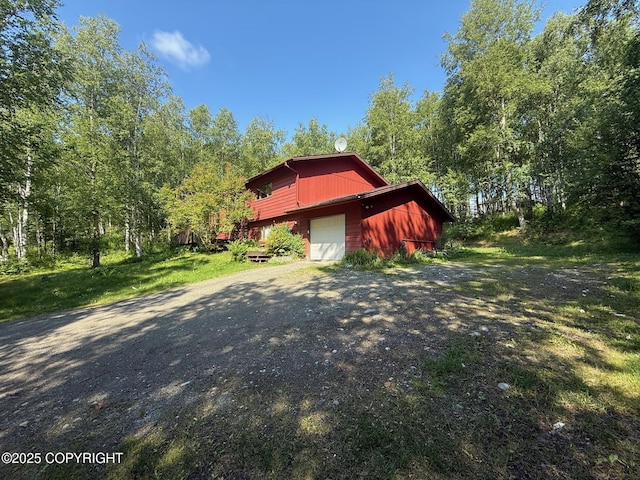4261 E Foxtrot Ave, Wasilla, AK 99654 - view of property exterior featuring a garage, an outbuilding, and dirt driveway