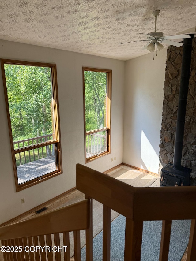 4261 E Foxtrot Ave, Wasilla, AK 99654 - unfurnished room with a textured ceiling, plenty of natural light, a wood stove, and a ceiling fan
