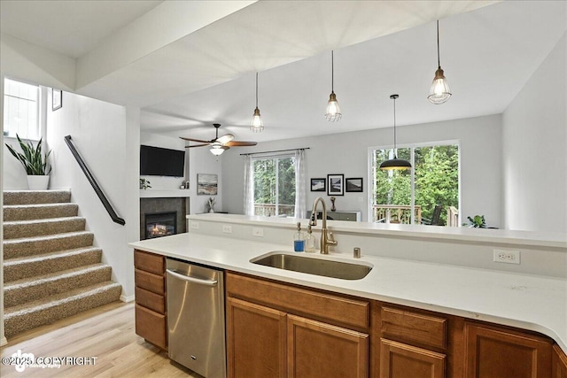20454 Icefall Dr, Eagle River, AK 99577 - kitchen featuring dishwasher, brown cabinetry, open floor plan, hanging light fixtures, and a glass covered fireplace