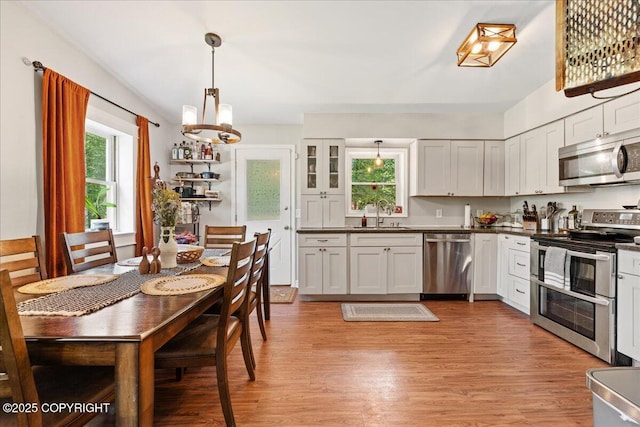 2701 Julie Ln, North Pole, AK 99705 - kitchen with stainless steel appliances, light wood-style floors, a chandelier, and dark countertops