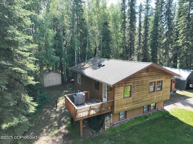 2701 Julie Ln, North Pole, AK 99705 - back of property featuring a storage shed, roof with shingles, a deck, and a view of trees