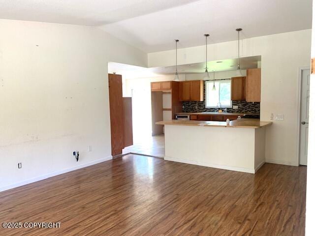 7367 S Rubacaba St, Wasilla, AK 99623 - kitchen featuring wood finished floors, backsplash, brown cabinetry, a peninsula, and pendant lighting