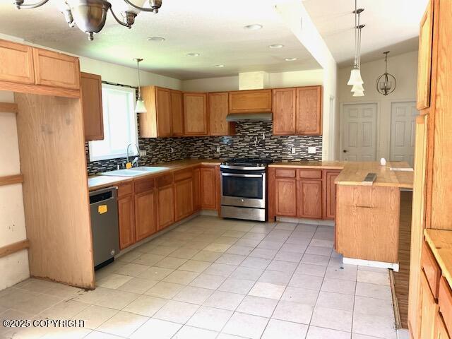 7367 S Rubacaba St, Wasilla, AK 99623 - kitchen with appliances with stainless steel finishes, decorative backsplash, light tile patterned floors, hanging light fixtures, and under cabinet range hood