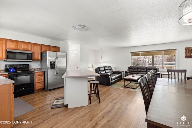 8430 Greenhill Way, Anchorage, AK 99502 - kitchen featuring appliances with stainless steel finishes, light countertops, light wood-type flooring, a kitchen bar, and open floor plan