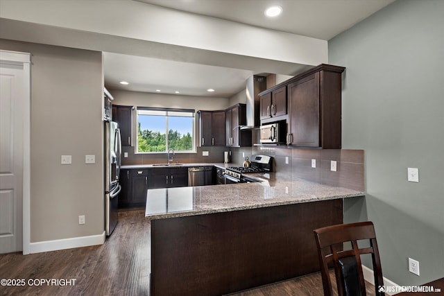 11459 Moonrise Ridge Pl # 7, Anchorage, AK 99516 - kitchen featuring appliances with stainless steel finishes, a peninsula, dark brown cabinetry, tasteful backsplash, and light stone counters