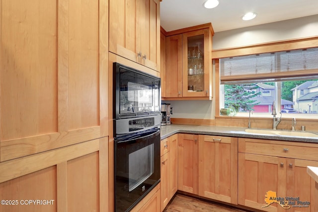 7521 Labrador Cir, Anchorage, AK 99502 - kitchen with black appliances, light brown cabinetry, glass insert cabinets, light wood-type flooring, and light stone countertops