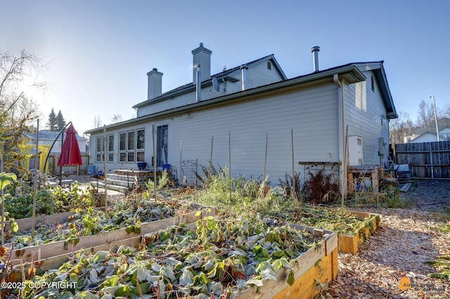 7521 Labrador Cir, Anchorage, AK 99502 - back of house featuring a vegetable garden and a chimney