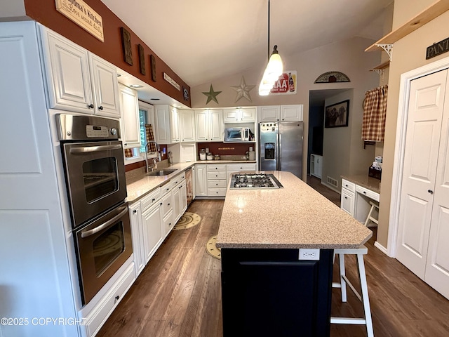 11741 Mary Ave, Anchorage, AK 99515 - kitchen featuring appliances with stainless steel finishes, vaulted ceiling, dark wood-style flooring, a center island, and white cabinets