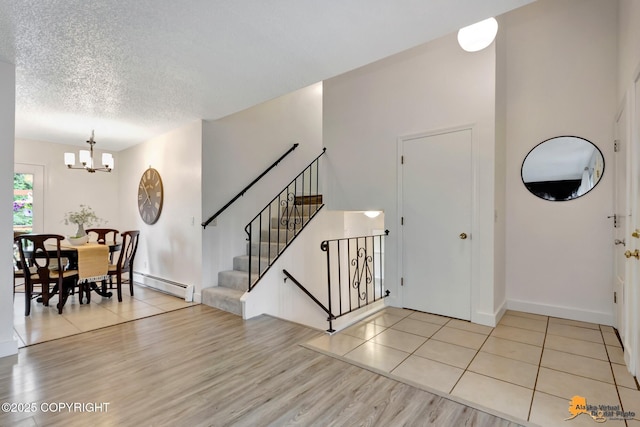 3116 Briarcliff Dr, Anchorage, AK 99508 - entrance foyer featuring a baseboard radiator, a chandelier, light wood finished floors, stairway, and a textured ceiling
