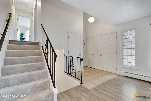 3116 Briarcliff Dr, Anchorage, AK 99508 - foyer featuring wood finished floors, plenty of natural light, stairs, a textured ceiling, and baseboard heating