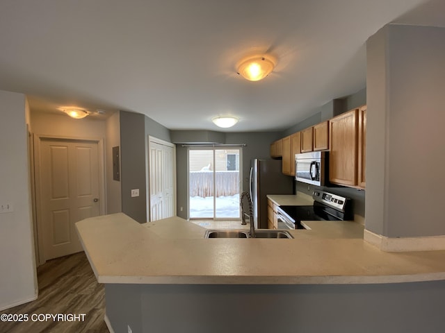 114 Rusty Allen Pl # 31, Anchorage, AK 99504 - kitchen featuring stainless steel appliances, light countertops, dark wood-style floors, a peninsula, and brown cabinets