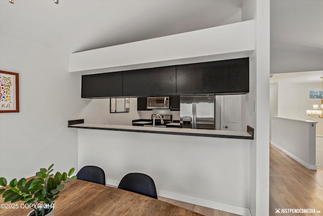 9755 Newhaven Loop, Anchorage, AK 99507 - kitchen with appliances with stainless steel finishes, a chandelier, wood finished floors, and lofted ceiling