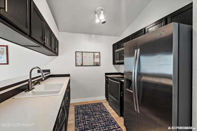 9755 Newhaven Loop, Anchorage, AK 99507 - kitchen with appliances with stainless steel finishes, dark cabinets, light wood-style floors, light countertops, and vaulted ceiling