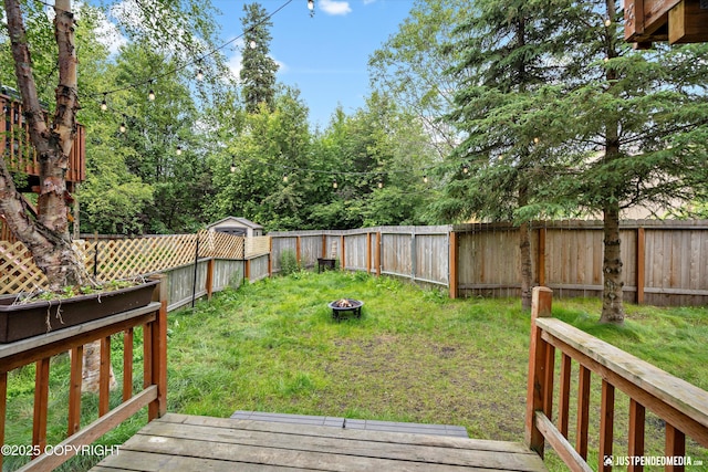 9755 Newhaven Loop, Anchorage, AK 99507 - fenced backyard featuring a wooden deck and a fire pit