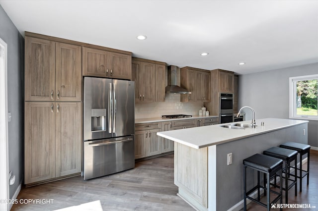 8410 E 20th Ave, Anchorage, AK 99504 - kitchen featuring stainless steel appliances, wall chimney exhaust hood, a center island with sink, a breakfast bar, and light countertops