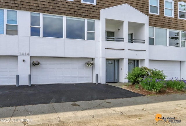 1414 W 7th Ave # 3, Anchorage, AK 99501 - view of front of home with a garage, asphalt driveway, and stucco siding