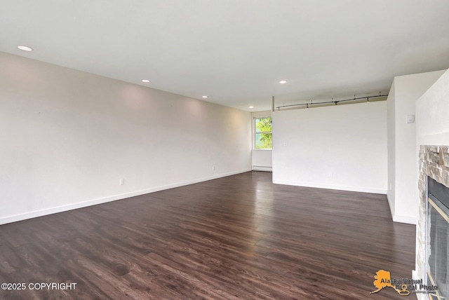 1414 W 7th Ave # 3, Anchorage, AK 99501 - unfurnished living room with a fireplace, dark wood-style flooring, recessed lighting, and a baseboard heating unit