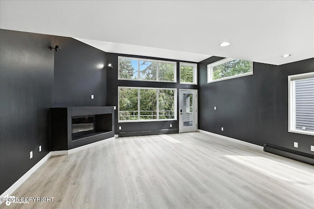 2433 La Honda Dr, Anchorage, AK 99517 - unfurnished living room with wood finished floors, a baseboard radiator, a glass covered fireplace, plenty of natural light, and recessed lighting