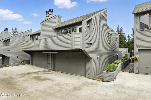 2433 La Honda Dr, Anchorage, AK 99517 - rear view of property with a balcony, a garage, driveway, and a chimney